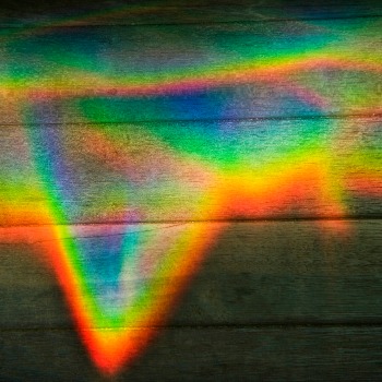 Abstract design of rainbow color prism on wood paneling.